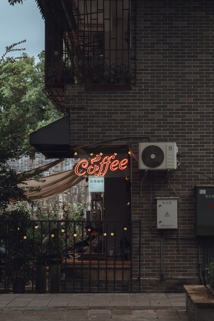 Cozy outdoor coffee shop with a glowing neon sign, offering a rustic urban ambiance.