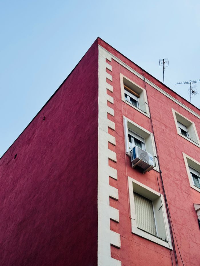 Corner view of vibrant urban building with antennas, air conditioner against a clear sky.